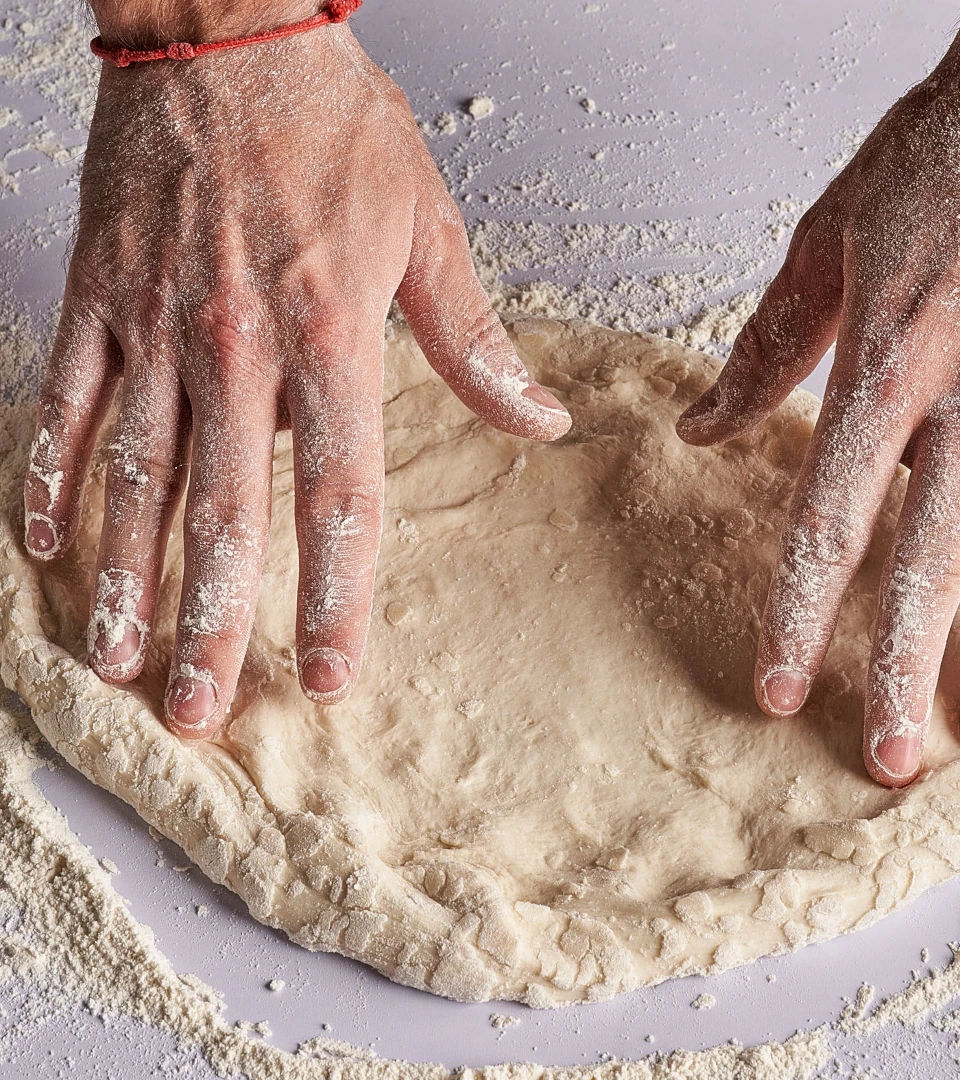 Manos amasando masa de pizza en un local de Papizza