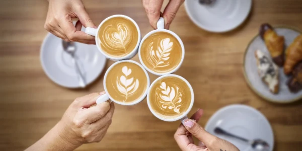 Manos sujetando tazas de café Santagloria