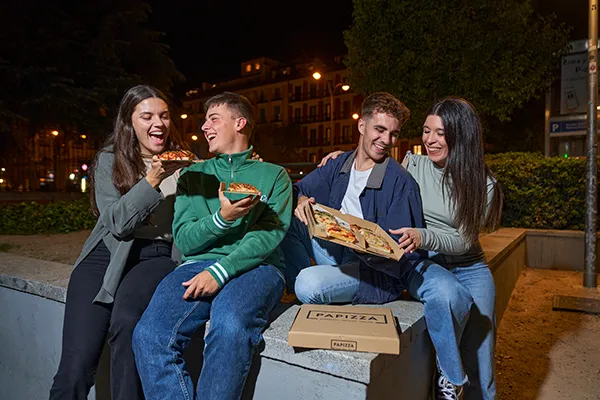 Grupo de amigos tomando pizzas de Papizza en la calle
