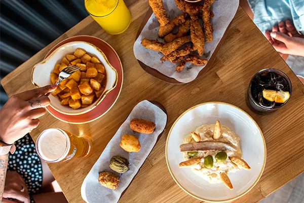 Mesa con platos y bebidas de la carta de M&aacute;sQMenos