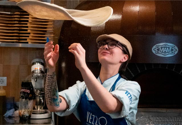 Cocinera lanzando la masa al aire en Vezzo