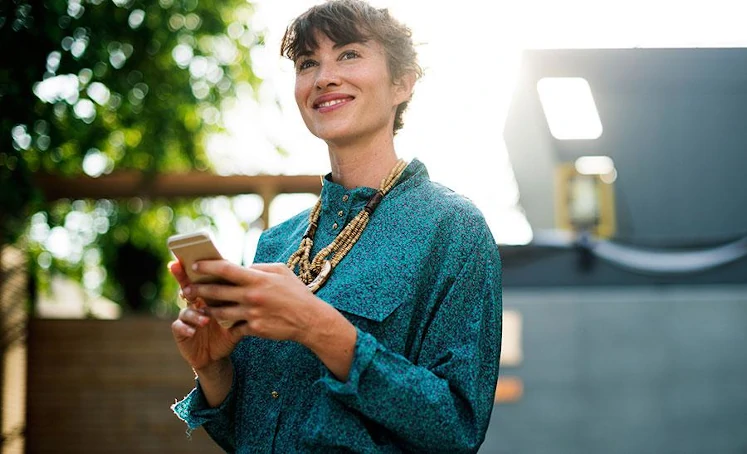 Mujer elegante sonriente mirando el m&oacute;vil